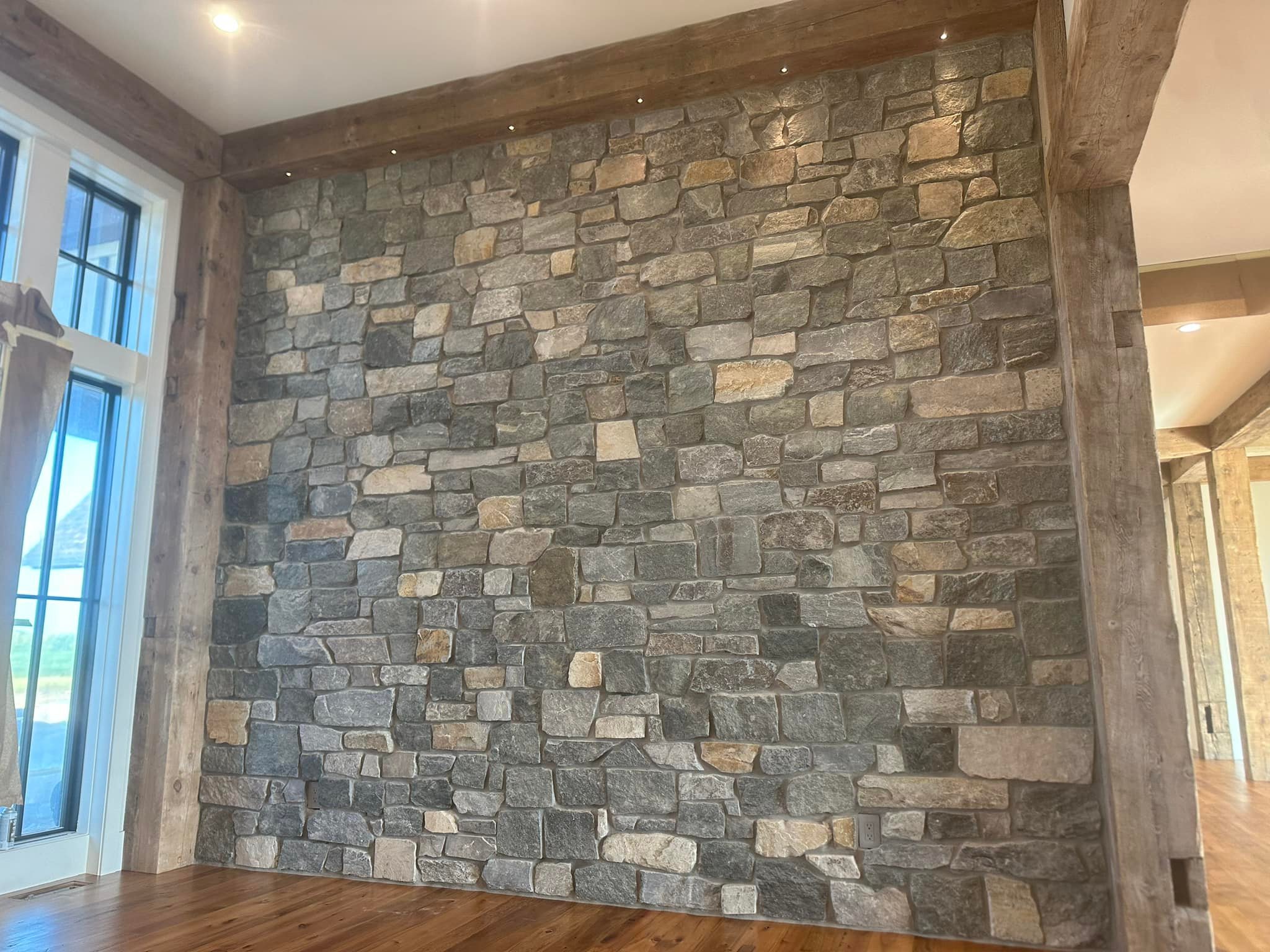 Finished stone feature wall with carefully fitted mixed stone, framed by substantial timber beams