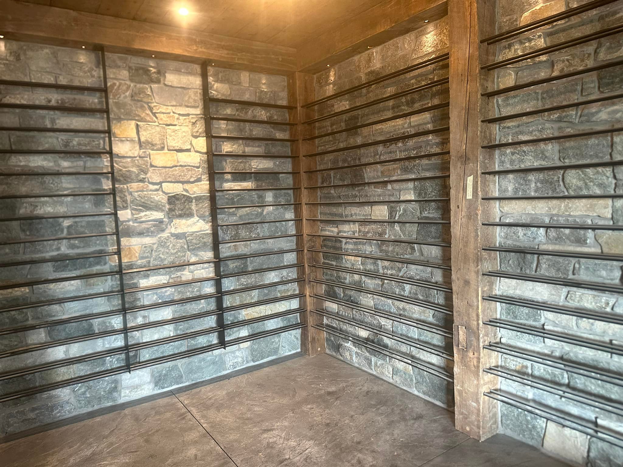 Natural stone walls and timber framing behind wine storage racks